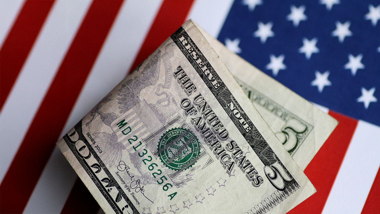 A U.S. five dollar note is seen atop the American Flag.