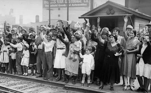 People on the side of railroad track, wave goodbye to Mexicans being expelled to Mexico.
