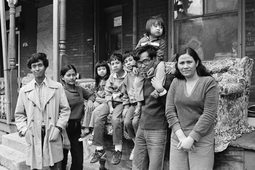 Photo showing a Cambodian refugee family standing in front of their home.