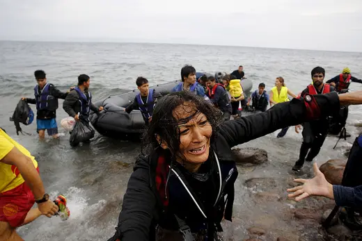 An exhausted Afghan migrant woman frantically looks for her children as she arrives on the Greek island of Lesbos in an overcrowded dinghy after crossing a part of the Aegean Sea