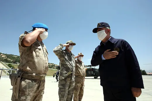 Three Turkish soldiers salute Defense Minister Hulusi Akar.