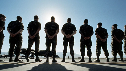 Line of american soldiers standing at U.S. military base. Aircrafts are seen in the distance.