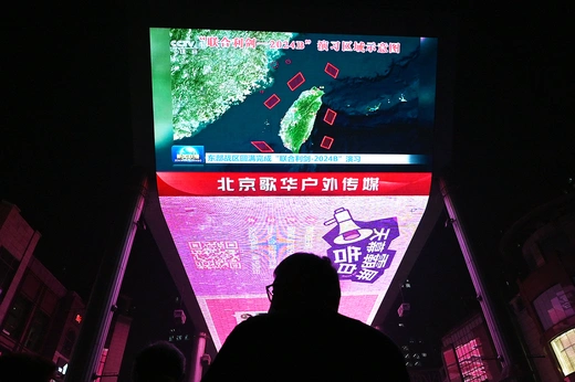 A man watches a news programme about Chinese military drills surrounding Taiwan, on a giant screen outside a shopping mall in Beijing on October 14, 2024.