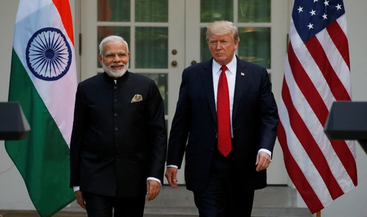 Indian Prime Minister Modi wears a black kurta while walking with U.S. President Trump, who wears a blue suit and red tie.